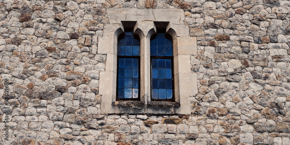 Old stone medieval wall with two windows in center
Old stone medieval wall with two windows in center