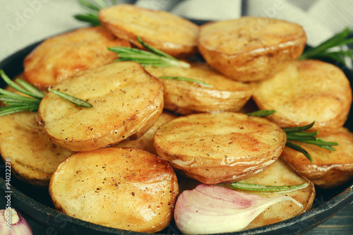 Delicious baked potato with rosemary in frying pan close up