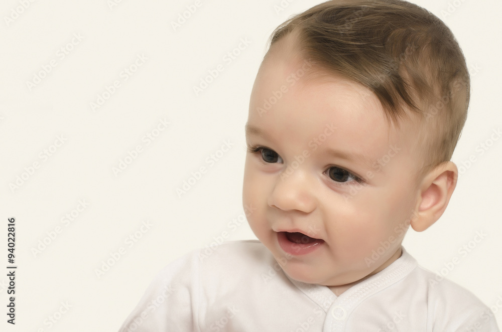 Cute baby boy looking down smiling. Adorable happy baby portrait looking curious isolated on white.