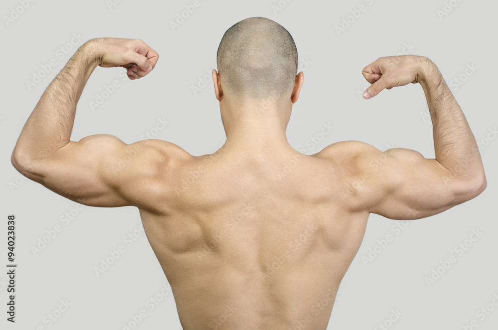 Topless man from the back raising his arms and fists.Fit bodybuilder showing his back muscles. Bald shaved man with big muscles, biceps, triceps and shoulders. Topless man from the back raising his arms and fists.Fit bodybuilder showing his back muscles. Bald shaved man with big muscles, biceps, triceps and shoulders.