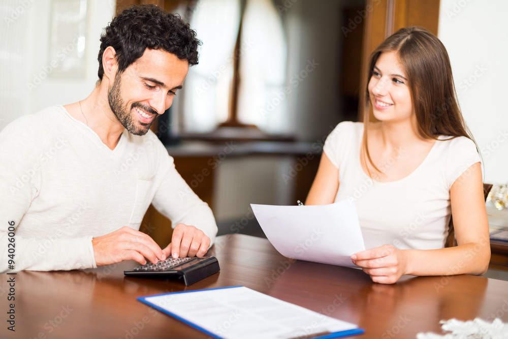Happy couple calculating their expenses Happy couple calculating their expenses