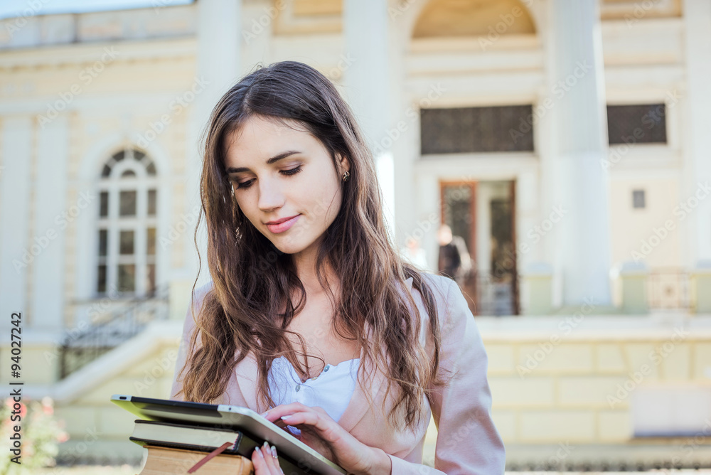 young caucasian female student with books and tablet on campus, student study in campus area young caucasian female student with books and tablet on campus, student study in campus area