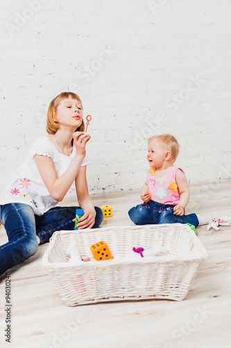 Nice girl blowing bubbles to her little sister photo