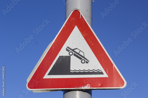 traffic sign at a harbor indicating the shore of a river 