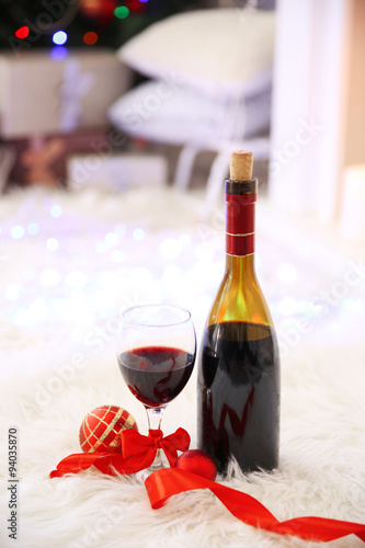 Fototapeta Naklejka Na Ścianę i Meble -  Bottle and glass of wine with Christmas decor against colorful bokeh lights background
