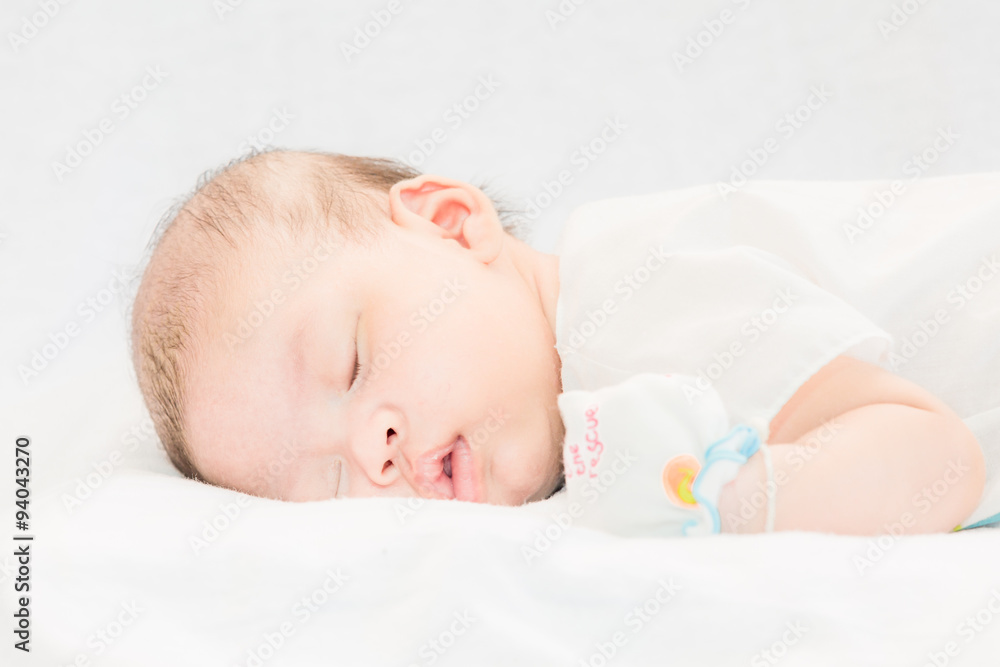 Peaceful baby lying on a bed while sleeping. Peaceful baby lying on a bed while sleeping.