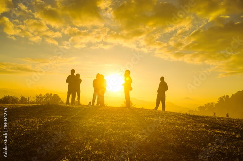 Group Of People relaxing on field with sunrise