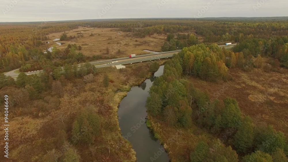 4K aerial view – flight over highway with river and colorful autumn forests on both sides 4K aerial view – flight over highway with river and colorful autumn forests on both sides