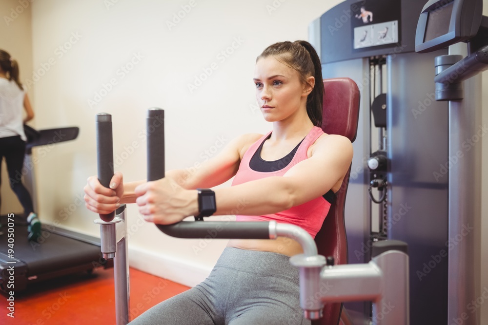 Fit woman using weights machine for arms Fit woman using weights machine for arms