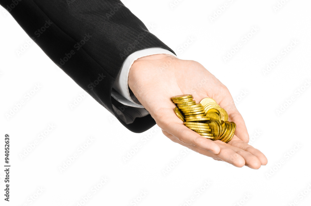 Fototapeta premium Money and business topic: hand in a black suit holding a pile of gold coins in the studio on a white background isolated