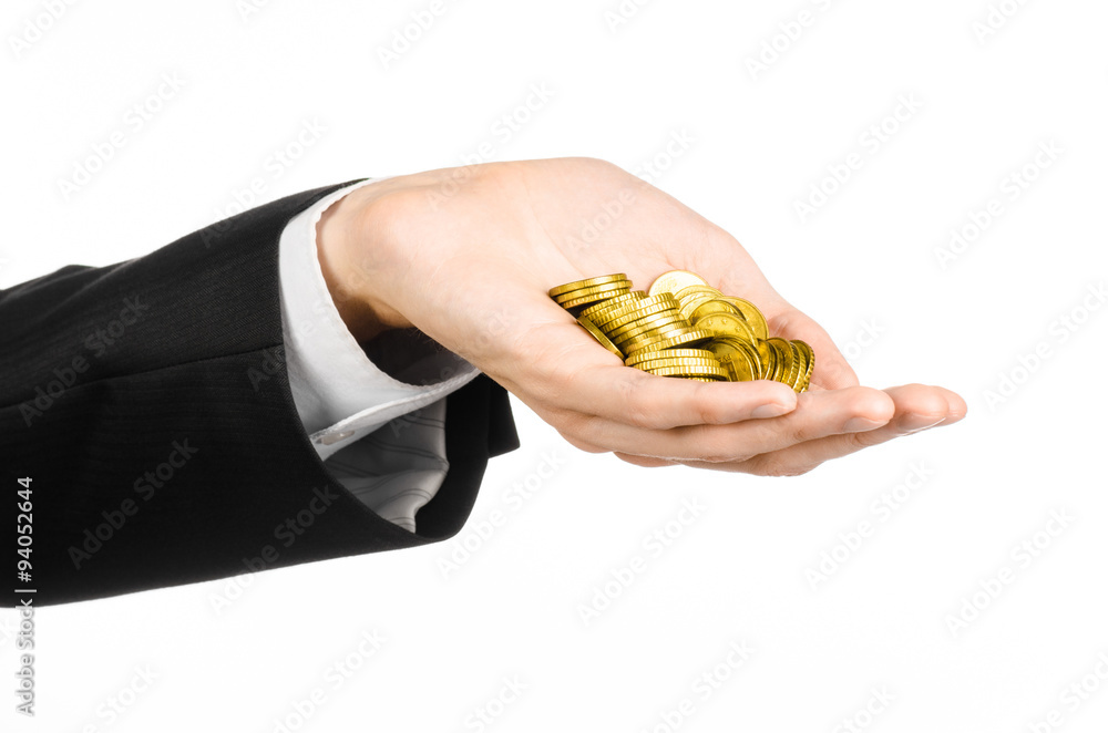 Obraz premium Money and business topic: hand in a black suit holding a pile of gold coins in the studio on a white background isolated