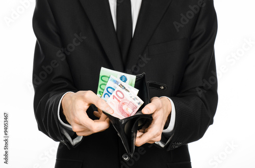 Money and business theme: a man in a black suit holding a purse with paper money Euro isolated on white background in studio