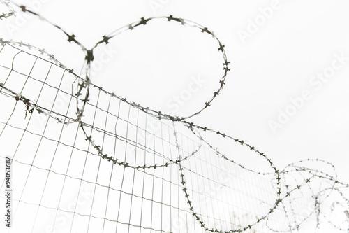 barb wire fence over gray sky