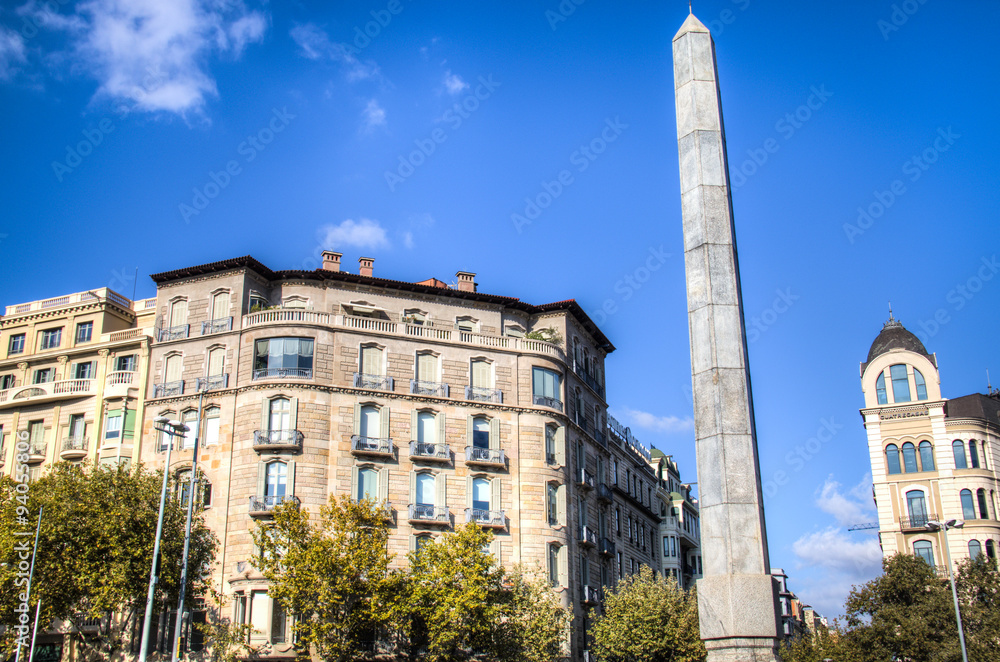 The obelisk and some historical buildings on Passeig de Gracia in Barcelona in Spain
