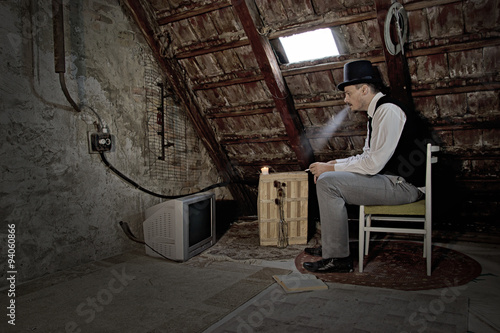 Vintage Man Watching TV Set in Old Attic Room and Smoking a Cigarette