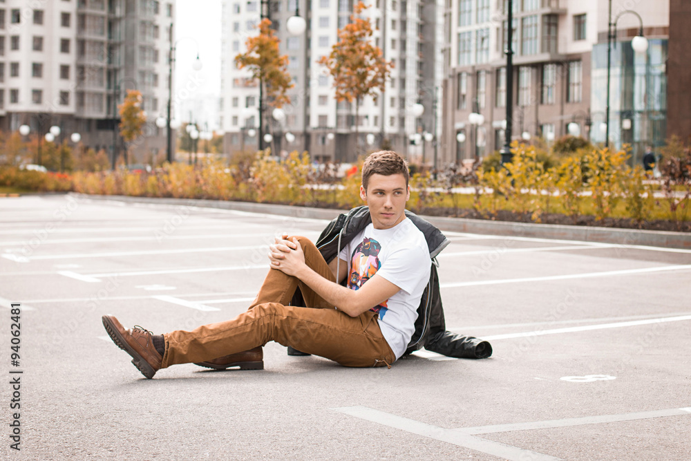 Handsome brown-haired young man posing on the ground. Autumn. Handsome brown-haired young man posing on the ground. Autumn.