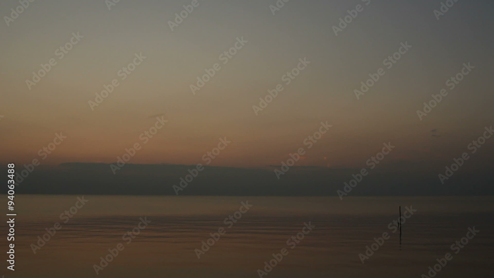The bright sun is setting over water with gentle waves The bright sun is setting over water with gentle waves