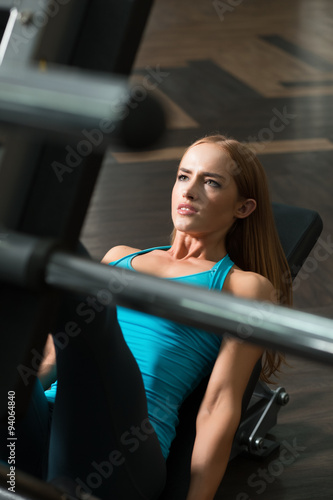 Strong woman lifting weight in gym. Leg press.