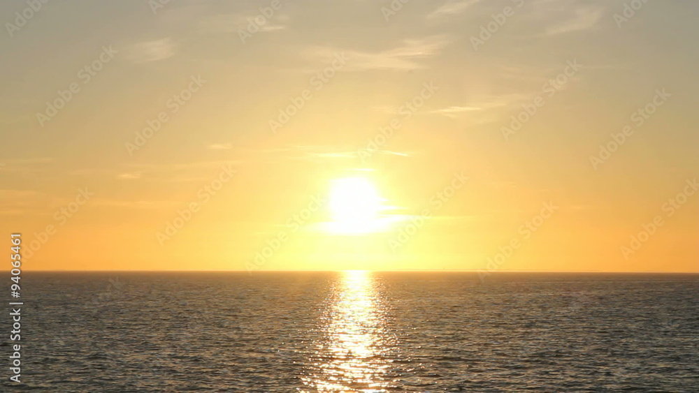 The bright sun is setting over water with gentle waves The bright sun is setting over water with gentle waves