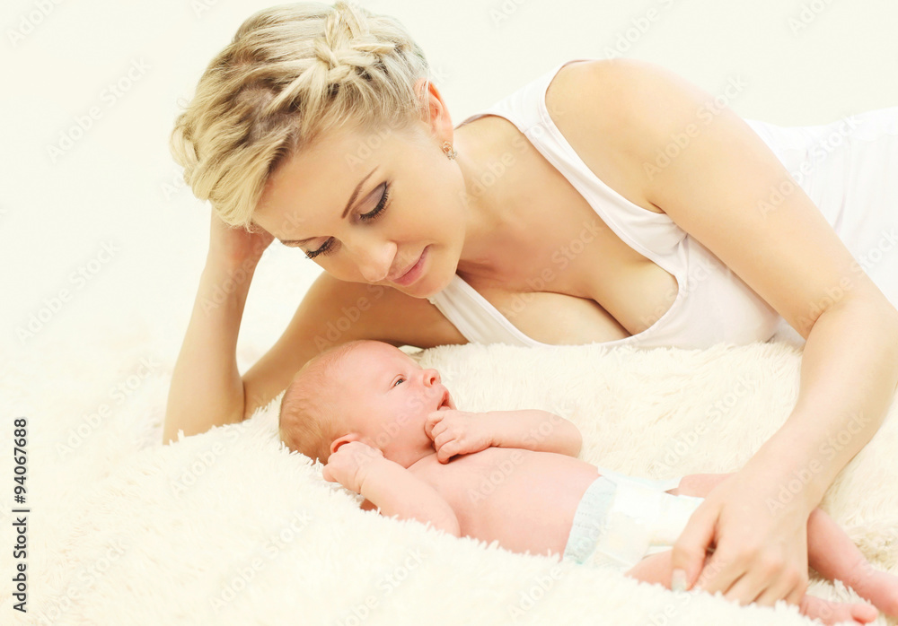 Happy mother with baby lying on bed together at home Happy mother with baby lying on bed together at home