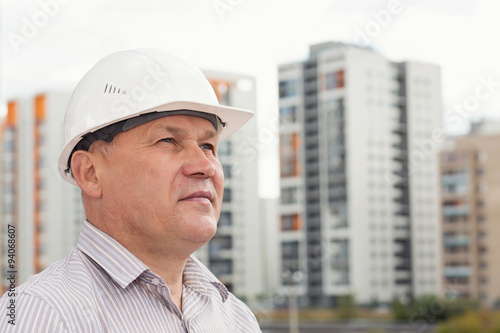 An engineer in white helmet on a background with buildings