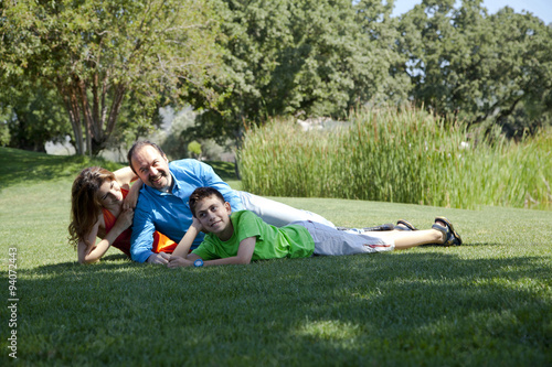 Happy family is lying down on the grass at park © COSPV