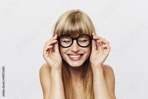 Happy young lady in glasses in white studio
