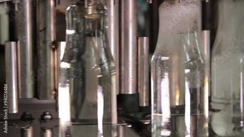 Glass bottles move on conveyor and filling by liquid photo