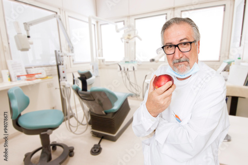 Senior dentist at her office with a apple