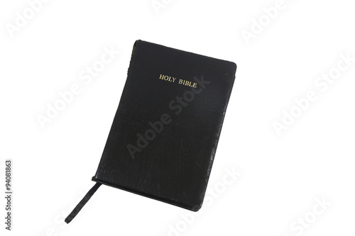 Holy Bible, gold leaf title on black simulated leather cover, closed, isolated on white. The bible is used and has some tearing to the spine.