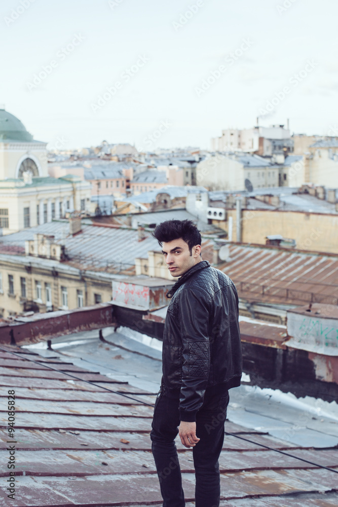 Man in a leather jacket on a rooftop in the center of the city