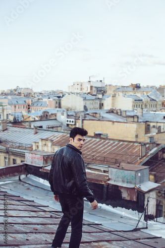 Man in a leather jacket on a rooftop in the center of the city