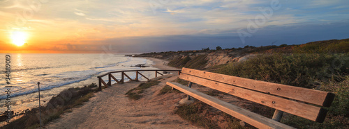 Bench along an outlook with a view at sunset of Crystal Cove Beach, Newport Beach and Laguna Beach line in Southern California photo
