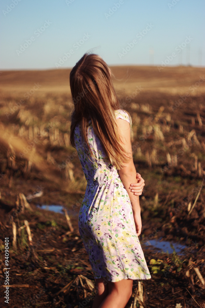 Obraz premium Beauty Romantic Girl Outdoors. Beautiful Teenage Model girl Dressed in Casual Dress on the Field in Sun Light. Blowing Long Hair. Autumn. Glow Sun, Sunshine. Toned in warm colors