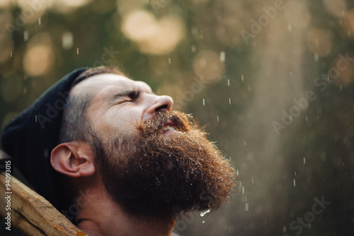 Foto bearded brutal man in warm hat lumberjack with an ax in a forest at sunset, and