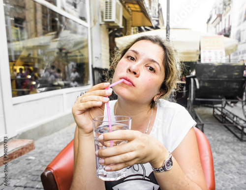 Young woman in street cafe with glass