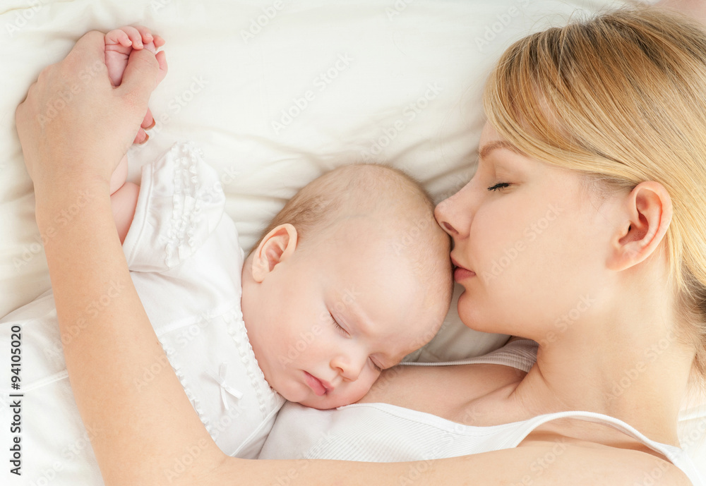 Young mother and her baby, sleeping in bed. Mother and baby. Hap Young mother and her baby, sleeping in bed. Mother and baby. Hap