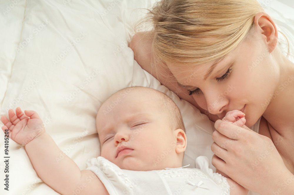 Young mother and her baby, sleeping in bed. Mother and baby. Hap Young mother and her baby, sleeping in bed. Mother and baby. Hap