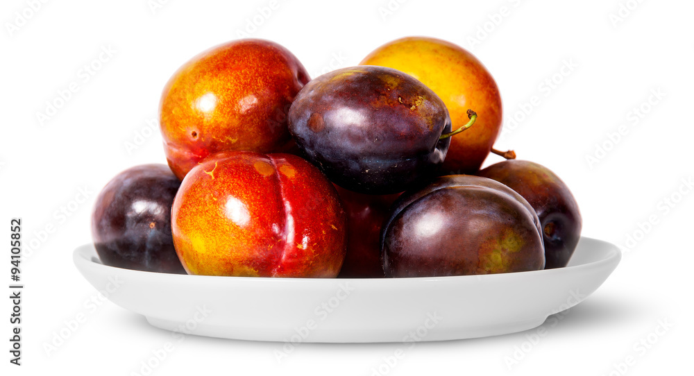 In front mix of red and violet plums on white plate In front mix of red and violet plums on white plate