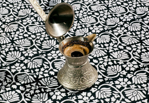 Cooper turkish Cezve with fresh coffee drink on tablecloth