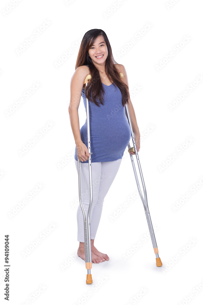 Full length portrait of a smiling pregnant woman using crutch , Full length portrait of a smiling pregnant woman using crutch ,