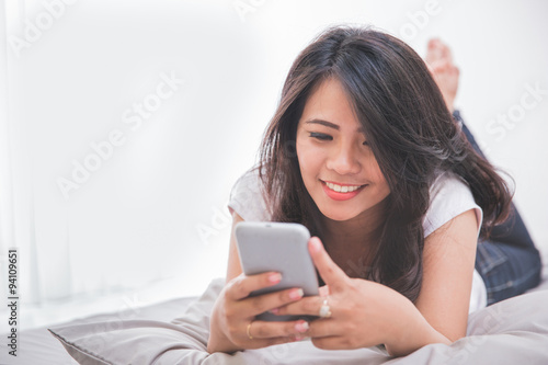 Woman using cellphone on the bed