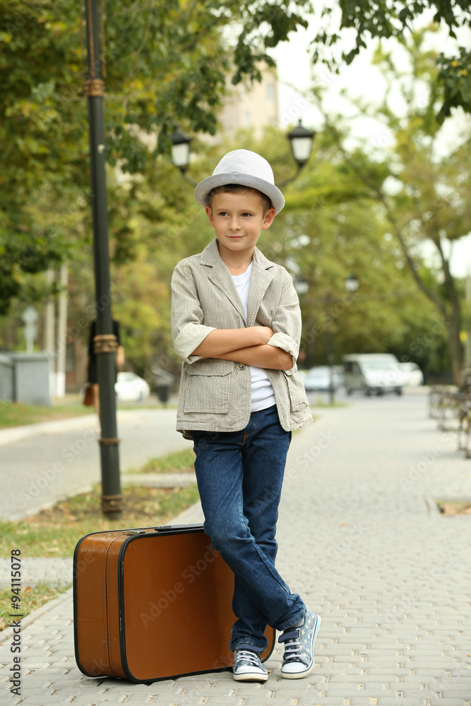 Fototapeta premium Little boy with suitcase in the park
