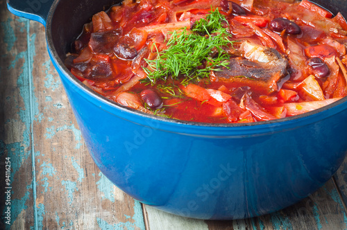 Traditional Ukrainian beetroot broth, known as Borshch, served on a rustic wooden table. A delicious vegetarian dish common in Eastern Europe.