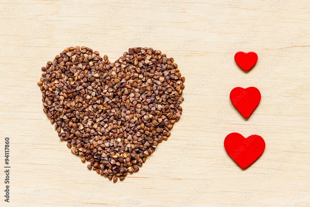 buckwheat groats heart shaped on wooden surface. buckwheat groats heart shaped on wooden surface.