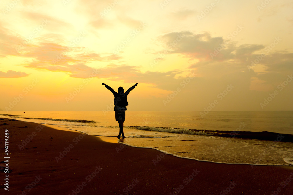 Stock Photo:. woman open arms under the sunset at sea