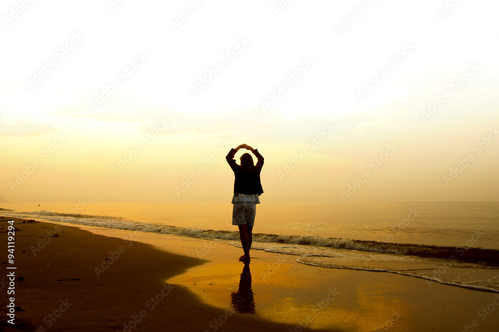 Stock Photo:.A woman standing on the beach near the sea and watc