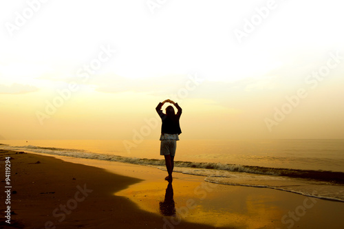 Stock Photo:.A woman standing on the beach near the sea and watc