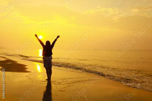 Stock Photo:. woman open arms under the sunset at sea photo