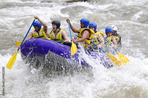 A group of men and women in a white raft navigating through the thrilling whitewater rapids of the Patate River in Ecuador, filled with action and fun.